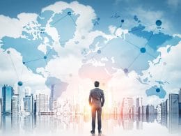 Dal rischio all’opportunità: come le PMI possono crescere in un mercato che cambia. Uomo in abito elegante osserva un panorama urbano con mappa globale sovrapposta, simbolo di connessioni internazionali, reti finanziarie e opportunità di business globali.
