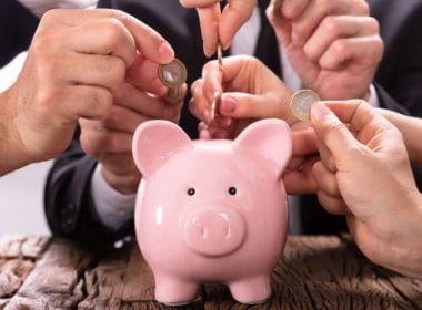 Crowdlending: come la tecnologia sta democratizzando l’accesso al credito e creando. Mani di più persone inseriscono monete in un salvadanaio rosa, simbolo del crowdlending e del finanziamento collettivo alle PMI. nuove opportunità di investimento