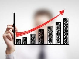 Finanza alternativa: opportunità e rischi per le PMI in cerca di liquidità. Mano disegna un grafico a barre in crescita con freccia rossa ascendente, simbolo di crescita finanziaria e successo di soluzioni alternative di investimento.