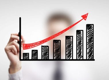 Finanza alternativa: opportunità e rischi per le PMI in cerca di liquidità. Mano disegna un grafico a barre in crescita con freccia rossa ascendente, simbolo di crescita finanziaria e successo di soluzioni alternative di investimento.