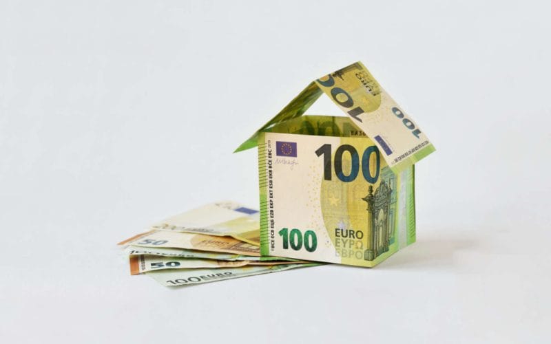 Crowdlending e cessione dei crediti fiscali: una nuova frontiera della finanza alternativa. Casa costruita con banconote da 100 euro su sfondo bianco, simbolo del finanziamento immobiliare tramite crowdlending e cessione dei crediti fiscali.