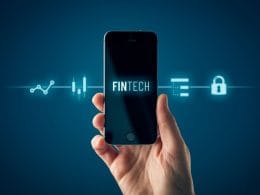 Tecnologia e finanza: l’impatto dell’intelligenza artificiale sulle decisioni economiche delle imprese. Mano tiene uno smartphone con la scritta “FINTECH” sullo schermo; intorno al dispositivo icone digitali che rappresentano dati, sicurezza e analisi finanziaria.