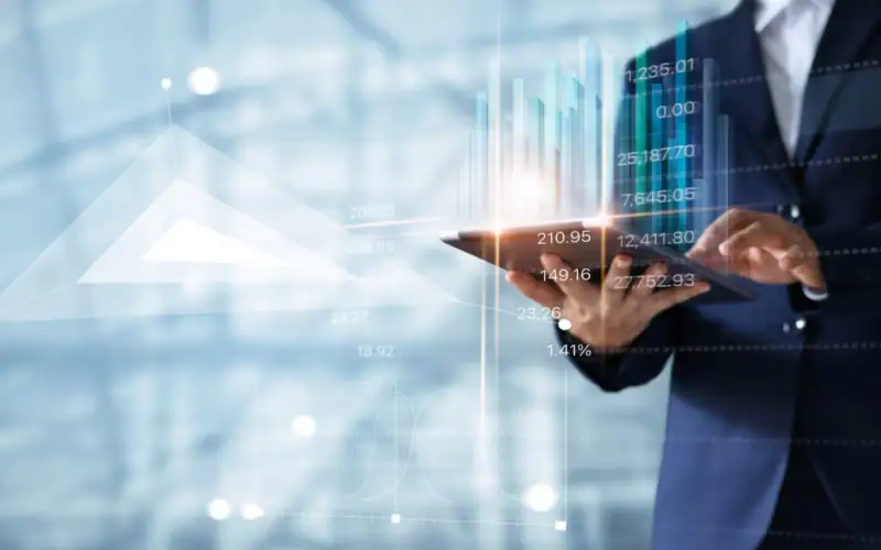 Oltre la banca: 5 strumenti finanziari alternativi che le PMI non stanno sfruttando. Professionista in abito formale utilizza un tablet con grafici digitali in sovrimpressione, rappresentazione della finanza tecnologica e analisi dei dati per l’accesso al credito.