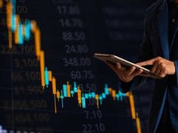 Mutui per aziende: quali scegliere e quando richiederli per far crescere il tuo business. Un uomo in giacca consulta un tablet davanti a un grafico di borsa in calo, simbolo della volatilità dei mercati e delle strategie finanziarie in tempo reale.