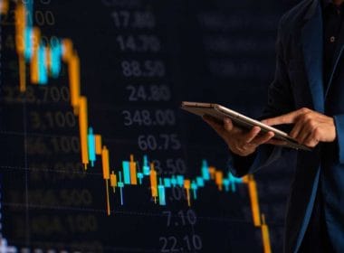 Mutui per aziende: quali scegliere e quando richiederli per far crescere il tuo business. Un uomo in giacca consulta un tablet davanti a un grafico di borsa in calo, simbolo della volatilità dei mercati e delle strategie finanziarie in tempo reale.