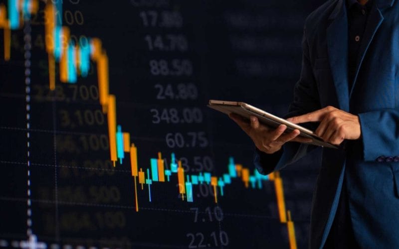 Mutui per aziende: quali scegliere e quando richiederli per far crescere il tuo business. Un uomo in giacca consulta un tablet davanti a un grafico di borsa in calo, simbolo della volatilità dei mercati e delle strategie finanziarie in tempo reale.