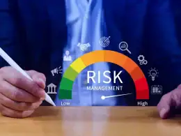 Costruire valore in tempi incerti: la gestione della liquidità come asset strategico. Mani di un professionista con penna digitale che interagisce con un indicatore di gestione del rischio colorato da verde a rosso, rappresentante il livello di rischio da basso ad alto.