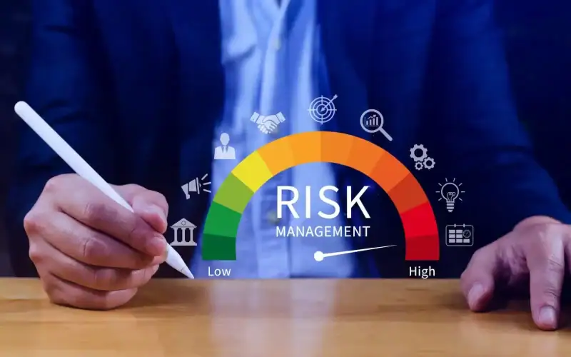Costruire valore in tempi incerti: la gestione della liquidità come asset strategico. Mani di un professionista con penna digitale che interagisce con un indicatore di gestione del rischio colorato da verde a rosso, rappresentante il livello di rischio da basso ad alto.