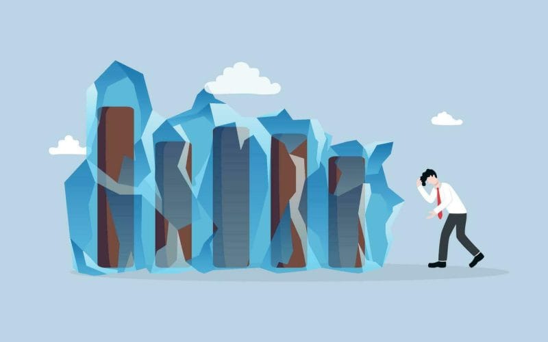 L’economia italiana nel 2025: resilienza o stagnazione? Illustrazione concettuale di un uomo d’affari preoccupato davanti a colonne di dati congelate nel ghiaccio, simbolo di crisi economica, blocco finanziario o stagnazione del business.