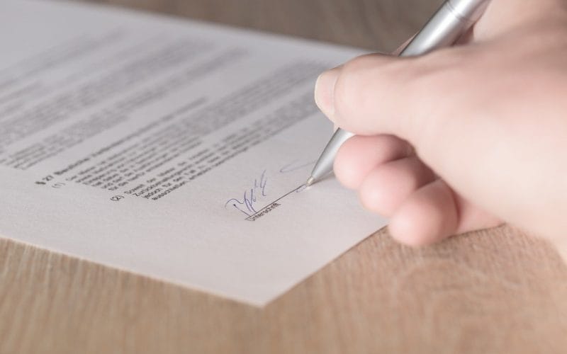 Mutui, prestiti e leasing: tutto quello che devi sapere prima di firmare. Mano che firma un contratto con penna su un foglio ufficiale: simbolo della decisione consapevole su mutuo, prestito o leasing.