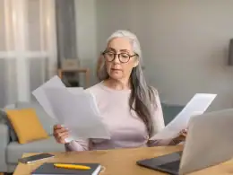 L’impatto del part-time sulla posizione contributiva e le possibili soluzioni per tutelare il diritto a pensione. Donna matura con capelli grigi e occhiali analizza documenti davanti a un computer portatile, valutando gli effetti del lavoro part-time sulla sua pensione.