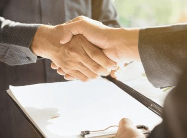 Pace contributiva: cos’è, chi può accedervi e quali periodi permette di recuperare. Stretta di mano tra due uomini d’affari con documenti su una cartelletta, simbolo di accordo o intesa contributiva.