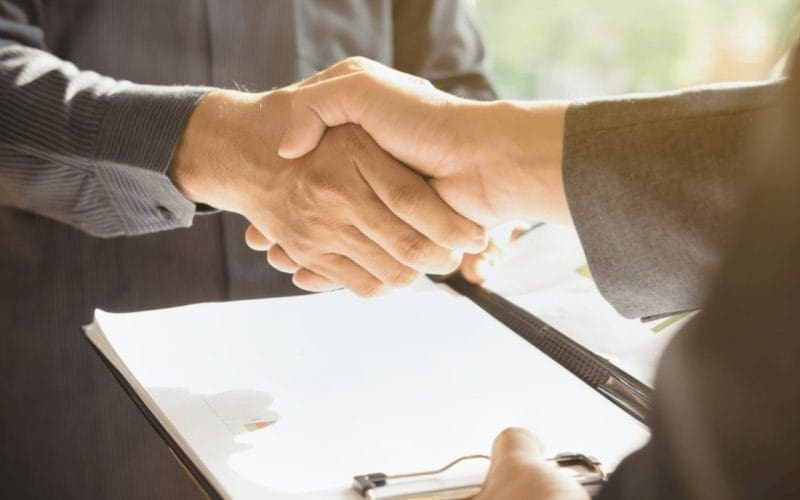 Pace contributiva: cos’è, chi può accedervi e quali periodi permette di recuperare. Stretta di mano tra due uomini d’affari con documenti su una cartelletta, simbolo di accordo o intesa contributiva.