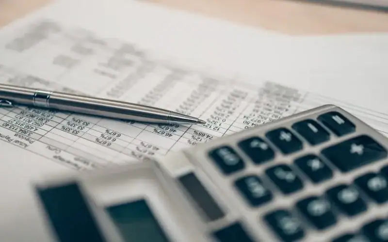 Periodi mancanti nell’estratto conto contributivo: quali strumenti ha a disposizione il lavoratore per tutelare i propri diritti pensionistici? Primo piano su calcolatrice e penna posate su un foglio con dati contributivi: simbolo dell’analisi dei periodi mancanti nell’estratto conto previdenziale INPS.