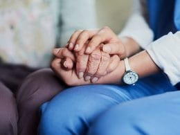 Come funziona l’Ape Sociale per chi assiste un familiare disabile grave? Due mani che si stringono: una giovane e una anziana, simbolo di assistenza familiare e cura nei confronti di persone con disabilità grave.
