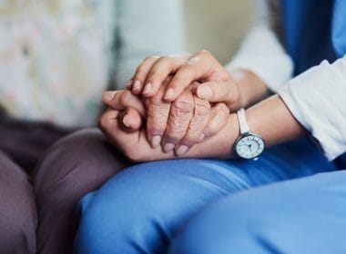 Come funziona l’Ape Sociale per chi assiste un familiare disabile grave? Due mani che si stringono: una giovane e una anziana, simbolo di assistenza familiare e cura nei confronti di persone con disabilità grave.