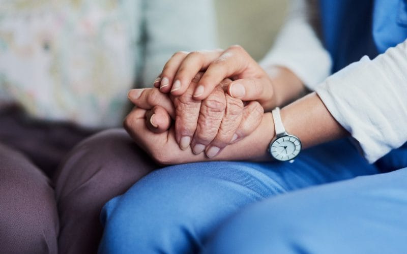 Come funziona l’Ape Sociale per chi assiste un familiare disabile grave? Due mani che si stringono: una giovane e una anziana, simbolo di assistenza familiare e cura nei confronti di persone con disabilità grave.