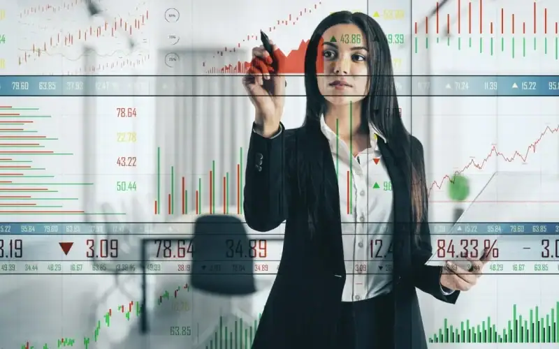 Dall’assicuratore al consulente multitasking: l’evoluzione dei professionisti della finanza. Donna in abito professionale che analizza grafici digitali di borsa e dati finanziari su un pannello trasparente virtuale, rappresentando l’uso della tecnologia nella consulenza finanziaria.