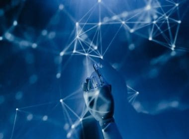 Insurtech e instant insurance: la rivoluzione delle polizze a portata di clic. Mano robotica che interagisce con una rete di connessioni digitali in un ambiente futuristico blu, simbolo di intelligenza artificiale, algoritmi e tecnologia avanzata.