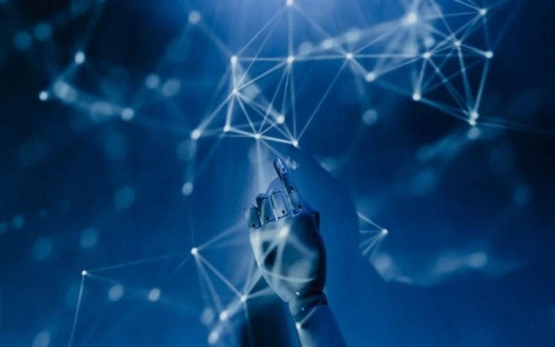 Insurtech e instant insurance: la rivoluzione delle polizze a portata di clic. Mano robotica che interagisce con una rete di connessioni digitali in un ambiente futuristico blu, simbolo di intelligenza artificiale, algoritmi e tecnologia avanzata.