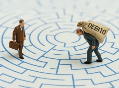 Due miniature di uomini in un labirinto: uno cammina leggero con una valigetta, l’altro piegato sotto un sacco marcato “DEBITO”, simbolo visivo del contrasto tra debito buono e debito cattivo.