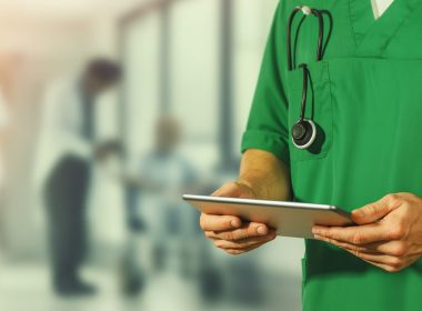 Quale futuro per le famiglie italiane? Medico in camice verde con tablet e stetoscopio, simbolo della spesa sanitaria