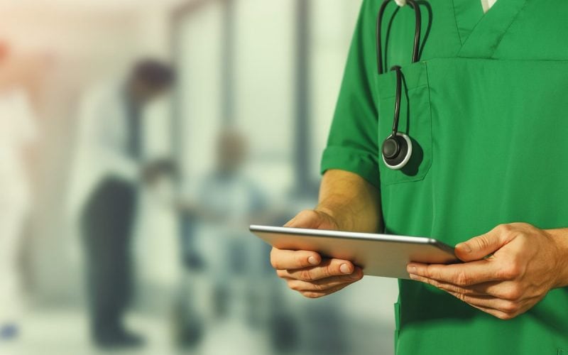 Quale futuro per le famiglie italiane? Medico in camice verde con tablet e stetoscopio, simbolo della spesa sanitaria