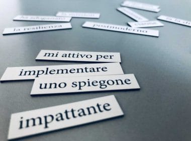 Frasi tipiche dell’aziendalese scritte su cartoncini bianchi disposti su un tavolo grigio