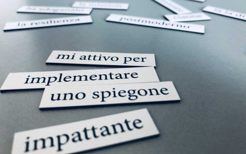 Frasi tipiche dell’aziendalese scritte su cartoncini bianchi disposti su un tavolo grigio