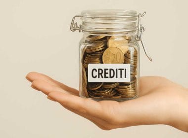 Barattolo di vetro pieno di monete con etichetta “CREDITI” appoggiato sul palmo di una mano, simbolo del credito d’imposta per l’innovazione 4.0 non ceduto.