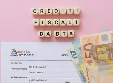Crediti fiscali da DTA con modulo Agenzia delle Entrate e banconote euro su sfondo rosa, concetto di agevolazioni fiscali.