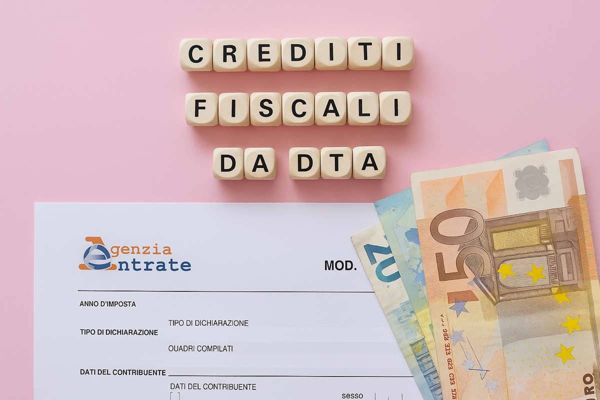 Crediti fiscali da DTA con modulo Agenzia delle Entrate e banconote euro su sfondo rosa, concetto di agevolazioni fiscali.