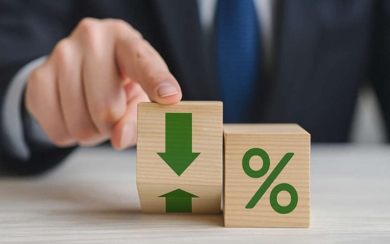 Il rating bancario: mano maschile in giacca e cravatta che indica blocchi di legno con simboli di percentuale e frecce