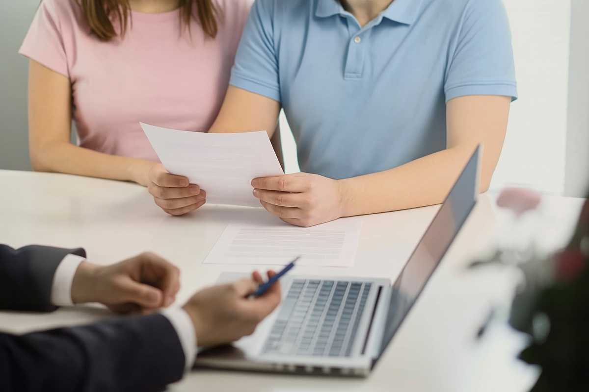 Negoziare meglio con la banca – coppia e consulente durante trattativa su documenti. Coppia che negozia con la banca tenendo documenti davanti a un consulente