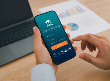 Persona al computer e smartphone con app di online banking, simbolo della guida ABI sui bonifici istantanei e sulla sicurezza dei pagamenti digitali.