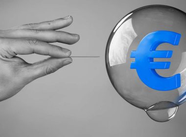 Mano con spillo pronta a far scoppiare una bolla con simbolo dell’euro blu, metafora delle bolle speculative nel mercato dell’arte da Van Gogh a Damien Hirst.