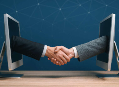 Due persone si stringono la mano attraverso schermi di computer rappresentando accordi digitali nei rischi lending crowdfunding