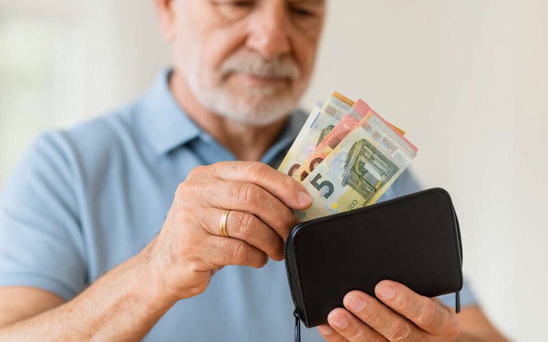 Uomo con portafoglio nero che conta contanti in casa