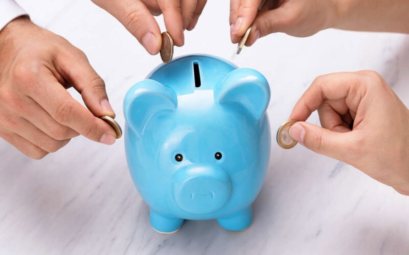 Persone che inseriscono monete in un salvadanaio azzurro, simbolo di lending crowdfunding