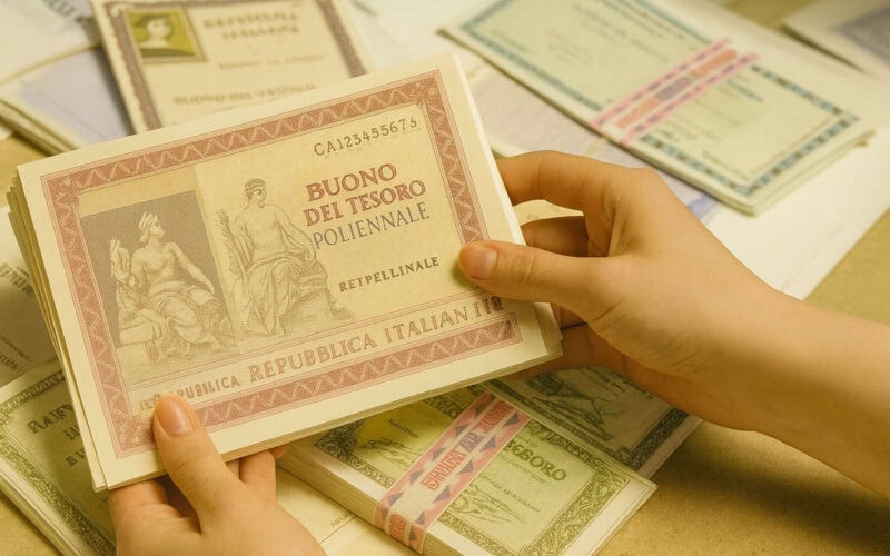 Mani femminili che tengono fascicoli di titoli di Stato e monetari italiani