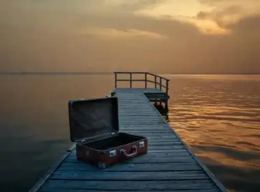 Pensione integrativa costi: valigia vuota abbandonata su un pontile al tramonto.