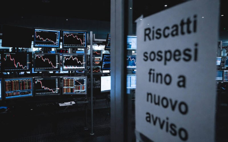 Fondi di private credit: sala trading con monitor in rosso e cartello "Riscatti sospesi fino a nuovo avviso"