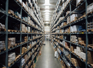 Corridoio di magazzino industriale con scaffali pieni di merci, esempio di cartolarizzazione magazzino senza pegno