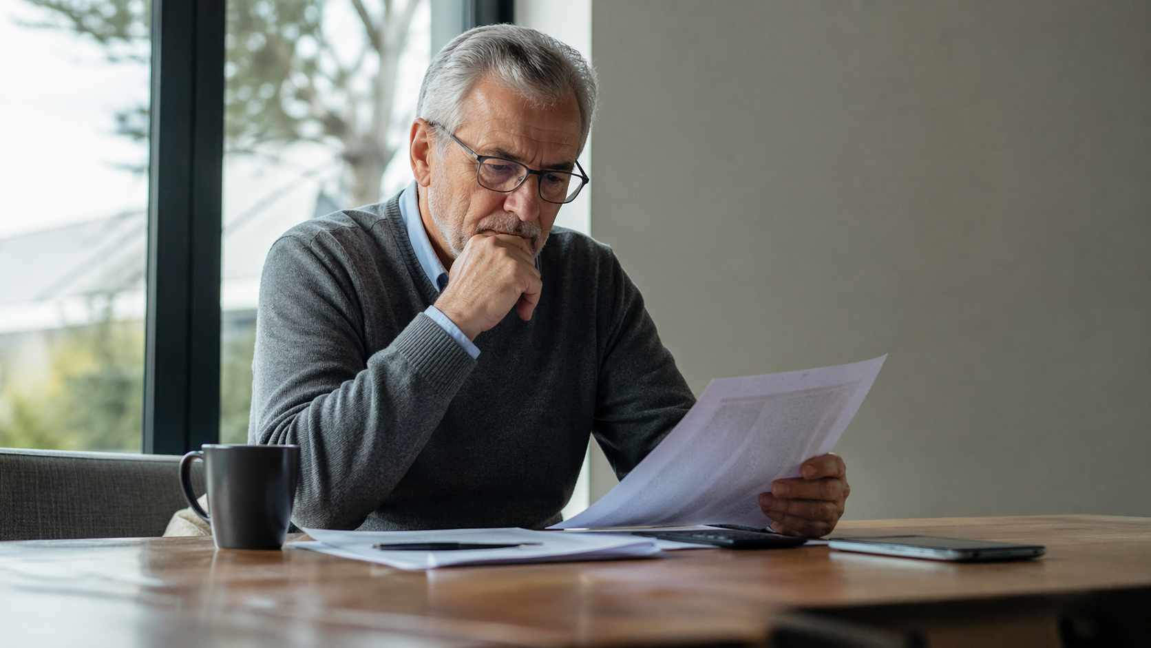 Uomo analizza documenti su pensione anticipata a 64 anni, valutando requisiti contributivi