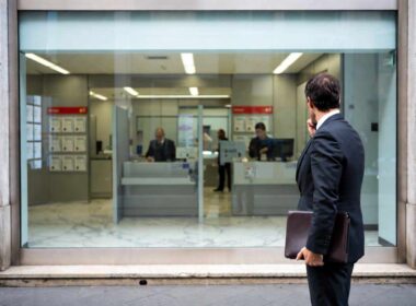 Reti terze credito: professionista indipendente davanti a una filiale bancaria vuota