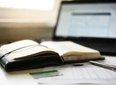 Spese sanitarie senza scontrino: tessera sanitaria, agenda e documenti fiscali su una scrivania con laptop sullo sfondo