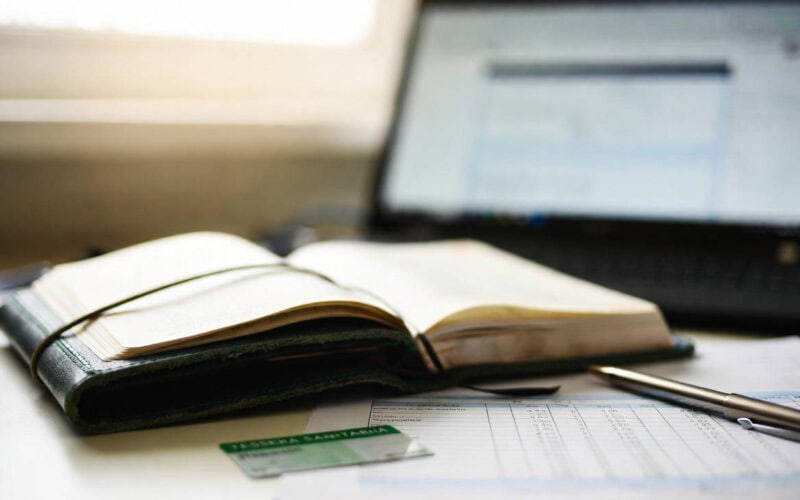 Spese sanitarie senza scontrino: tessera sanitaria, agenda e documenti fiscali su una scrivania con laptop sullo sfondo