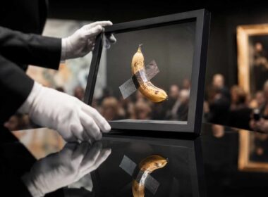 Mercato dell’arte contemporanea, banana incorniciata ispirata a Comedian esposta durante un’asta con pubblico sullo sfondo
