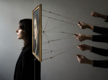 Investire in arte contemporanea: ritratto dipinto sorretto da fili tenuti da più mani, simbolo del sistema di legittimazione