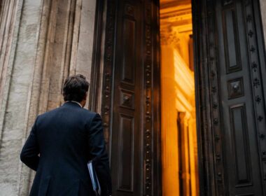 Finanziamenti PMI 2026: guida completa agli incentivi. Finanziamenti agevolati PMI 2026, imprenditore davanti all’ingresso di una banca prima di richiedere credito per investimenti